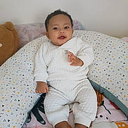 Alessio a rejoint le concours — aidez-le/la à gagner de superbes lots ! baby, child, smiling, white_outfit, pillow, cushion, plush_toy, indoor, patterned_blanket, happy, sitting, barefoot, cute, young_child, face, head, soft_toys, cozy, infant, home
