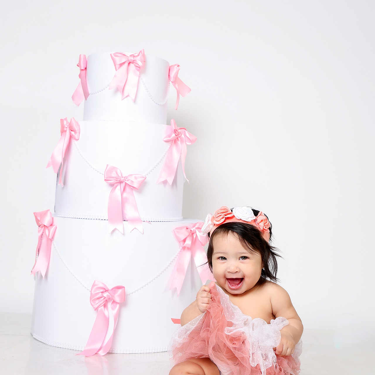 Nala is registered to the contest to win money with this photo: baby, child, girl, smiling, sitting, dress, headband, pink, ribbons, gift_box, white_background, happy, floor, portrait, cute, celebration, studio_photo, toddler, frilly_dress, indoor