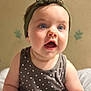 baby, child, face, headband, polka_dot, dress, sitting, blue_eyes, expression, indoor, soft_light, skin, infant, cute, young, person, portrait, clothing, background, happy