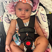 Amara is registered to the contest to win money with this photo: baby, child, car_seat, headband, floral_pattern, straps, sitting, infant, seatbelt, cute, serious_expression, indoor, closeup, person, colorful, soft_fabric, comfort, small_child, portrait, seat