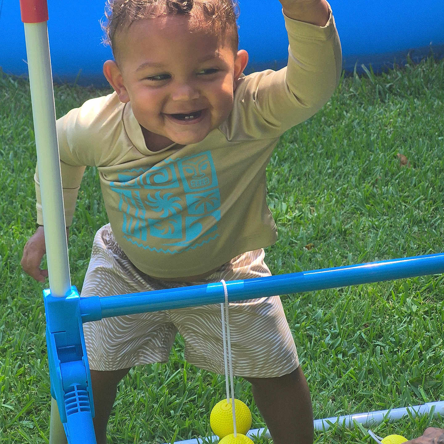 Marcus is registered to the contest to win money with this photo: toddler, child, smiling, outdoor, grass, barefoot, toy, plastic, play, game, yellow, ball, green, happy, person, clothing, shorts, long_sleeve, curly_hair, summer