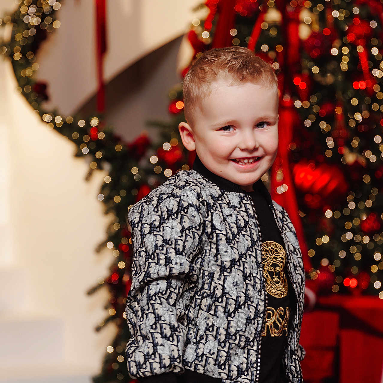 Adam is registered to the contest to win money with this photo: background, boy, celebration, child, christmas_tree, clothing, cute, face, fashion, festive, happy, holiday_decor, indoor, jacket, lights, portrait, red_ribbons, seasonal, smiling, young