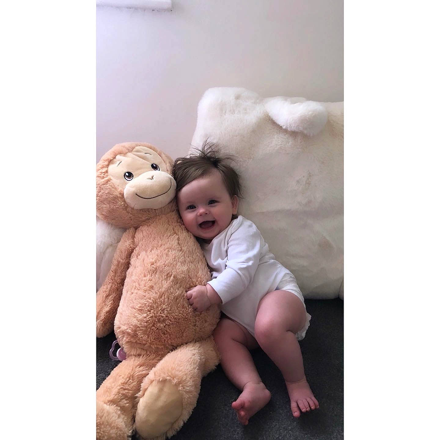 Harper is registered to the contest to win money with this photo: baby, baby_toddler_clothing, baby_toys, child, comfort, face, foot, fur, gesture, happy, human_body, linens, person, plush, room, sitting, smile, stuffed_toy, teddy_bear, toddler