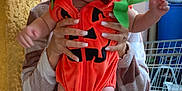 Aïlys participe au concours pour gagner de l'argent avec cette photo : baby, pumpkin_costume, child, person, hands, orange, hood, cute, wide_eyes, sitting, adult, manicured_nails, texture, yellow_tape, background, bench, household_items, socks, legs, casual_clothing