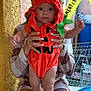 baby, pumpkin_costume, child, person, hands, orange, hood, cute, wide_eyes, sitting, adult, manicured_nails, texture, yellow_tape, background, bench, household_items, socks, legs, casual_clothing