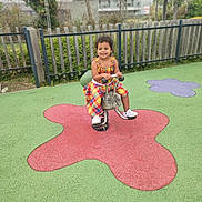 Lana a rejoint le concours — aidez-le/la à gagner de superbes lots ! child, colorful_dress, curly_hair, daylight, fence, fun, greenery, happy, outdoor, park, person, play_surface, playground, purple_shape, recreation, red_shape, shoes, smiling, spring_rider, young_child