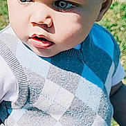 Kraylen is registered to the contest to win money with this photo: baby, child, toddler, face, eyes, sweater_vest, argyle_pattern, blue, gray, outdoor, grass, portrait, close_up, curious, young_child, skin, head, person, clothing, daylight