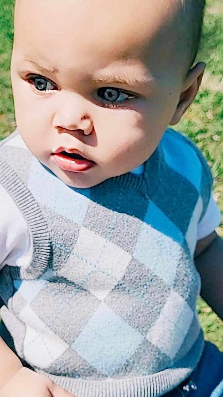 Kraylen is registered to the contest to win money with this photo: baby, child, toddler, face, eyes, sweater_vest, argyle_pattern, blue, gray, outdoor, grass, portrait, close_up, curious, young_child, skin, head, person, clothing, daylight
