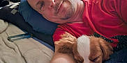 Bell is registered to the contest to win money with this photo: man, dog, sleeping, bed, pillow, red_shirt, blanket, indoor, relaxing, cozy, pet, portrait, face, rest, animal, cuddling, home, casual, comfort, laying_down