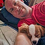 man, dog, sleeping, bed, pillow, red_shirt, blanket, indoor, relaxing, cozy, pet, portrait, face, rest, animal, cuddling, home, casual, comfort, laying_down