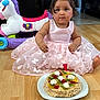 Agathe participe au concours pour gagner de l'argent avec cette photo : toddler, birthday, cake, crown, pink_dress, toy_horse, floor, celebration, child, cake_candle, fruit, kiwi, strawberry, cream, plate, indoor, curious, dress, party, first_birthday