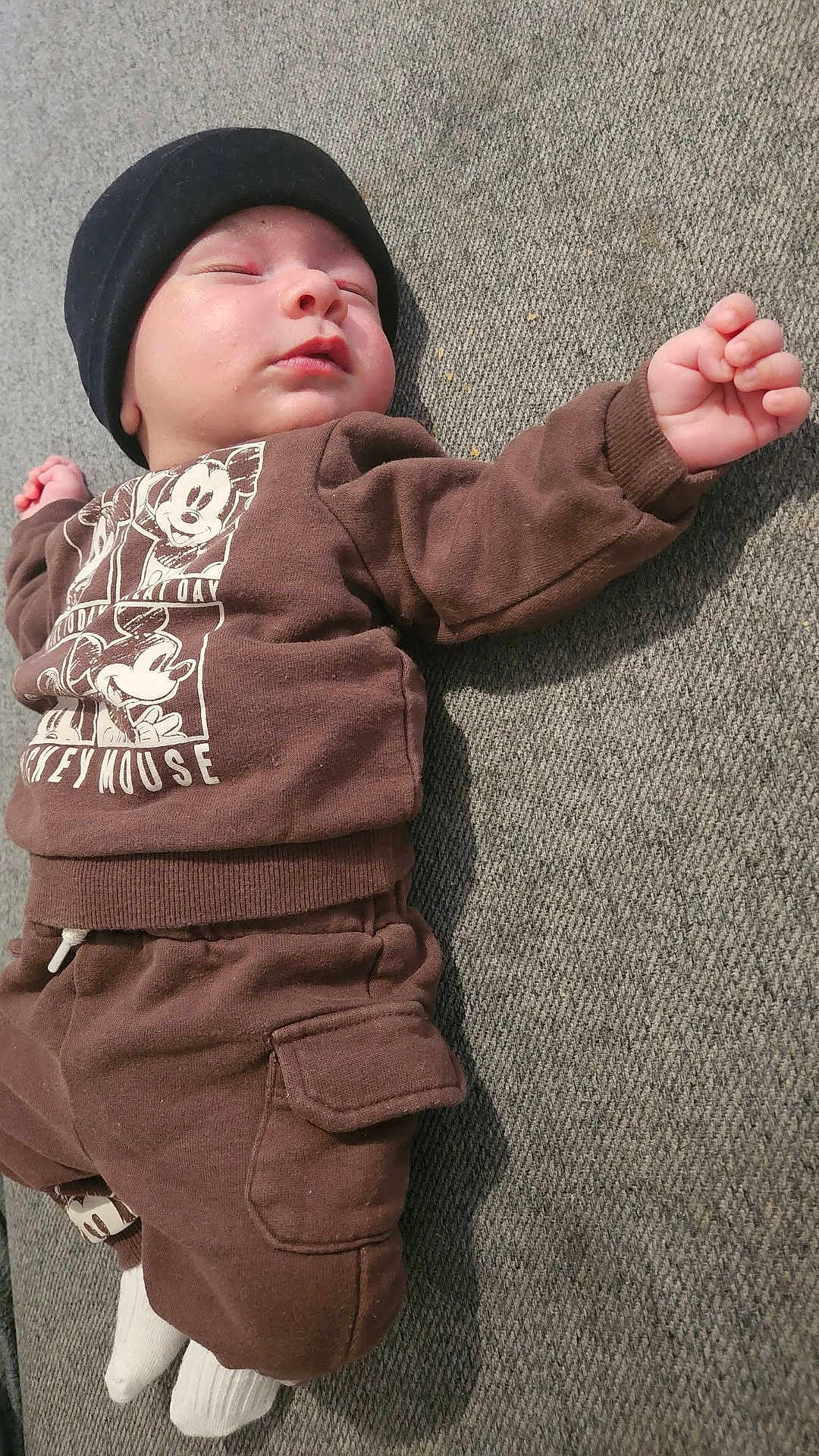 Sayf a rejoint le concours — aidez-le/la à gagner de superbes lots ! baby, infant, newborn, sleeping, hat, beanie, mickey_mouse, sweatshirt, pants, socks, hand, face, closed_eyes, lying_down, couch, fabric_texture, cozy, home_interior, soft_lighting, cute
