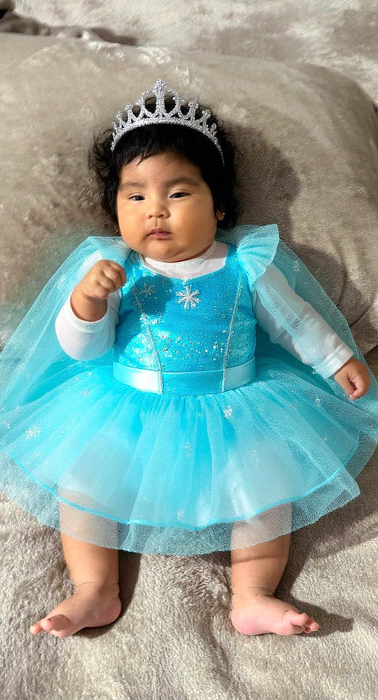 Luhara is registered to the contest to win money with this photo: baby, child, tutu, tiara, dress, blue_dress, sparkles, cute, infant, portrait, indoors, blanket, soft_texture, sitting, person, adorable, costume, celebration, young, fun
