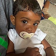 Dawn is registered to the contest to win money with this photo: toddler, child, pacifier, bottle, couch, curly_hair, white_clothing, indoor, closeup, baby, person, young_child, relaxed, cute, portrait, skin, hand, furniture, comfort, sitting