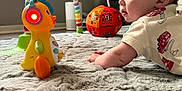 Carson is registered to the contest to win money with this photo: baby, toy, carpet, room, window, light, colorful, headphones, duck, floor, child, playing, indoor, soft, curious, crawling, orange, red, white, furniture