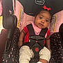 baby, car_seat, infant, child, red_bow, pink, black, seatbelt, strapped, wide_eyes, looking, indoors, clothing, socks, legs, face, head, cute, safety, person