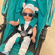 Demarcus is registered to the contest to win money with this photo: baby, sunglasses, stroller, hat, child, teal, clothing, sitting, cute, infant, casual, footwear, smiling, person, babywear, babyclothes, outdoor, comfort, accessory, seatbelt