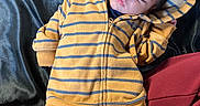 Demarcus is registered to the contest to win money with this photo: baby, sleeping, hoodie, yellow, blue_stripes, infant, child, cozy, fabric, blanket, clothing, rest, peaceful, cute, portrait, person, indoor, soft, casual, relaxation