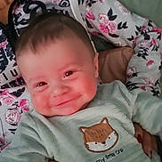 Eliam a rejoint le concours — aidez-le/la à gagner de superbes lots ! baby, smiling, infant, person, hand, clothing, hoodie, floral_pattern, couch, indoor, cute, portrait, child, young, holding, face, happy, cozy, casual, cute_outfit