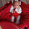 Nakyla Jones is registered to the contest to win money with this photo: adorable, baby, child, cozy, cute, flooring, hair_bows, indoor, infant, looking_up, playful_expression, plush_blanket, portrait, red_blanket, red_clothing, sitting, small_hands, tights, warm_colors, white_bows
