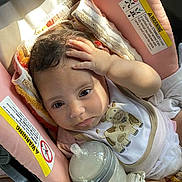 Alora joined the competition — help win amazing prizes! baby, infant, bottle, bib, car_seat, cushion, face, hand, milk, clothing, cute, child, seat, blanket, indoor, person, resting, expression, feeding, soft