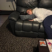 Sebastian is registered to the contest to win money with this photo: person, cat, couch, leather, pet_bed, glasses, hoodie, carpet, treadmill, table, coaster, butterfly, indoor, resting, relaxed, curled_up, black_cat, home, casual, comfort