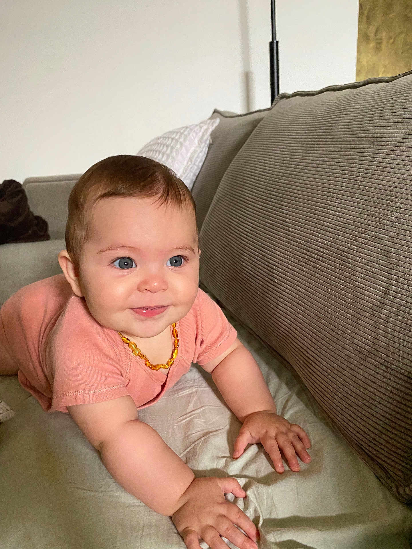 Aprile a rejoint le concours — aidez-le/la à gagner de superbes lots ! baby, blue_eyes, child, couch, crawling, cute, expression, face, furniture, hands, home, indoor, infant, necklace, peach_clothing, person, pillow, skin, smiling, young