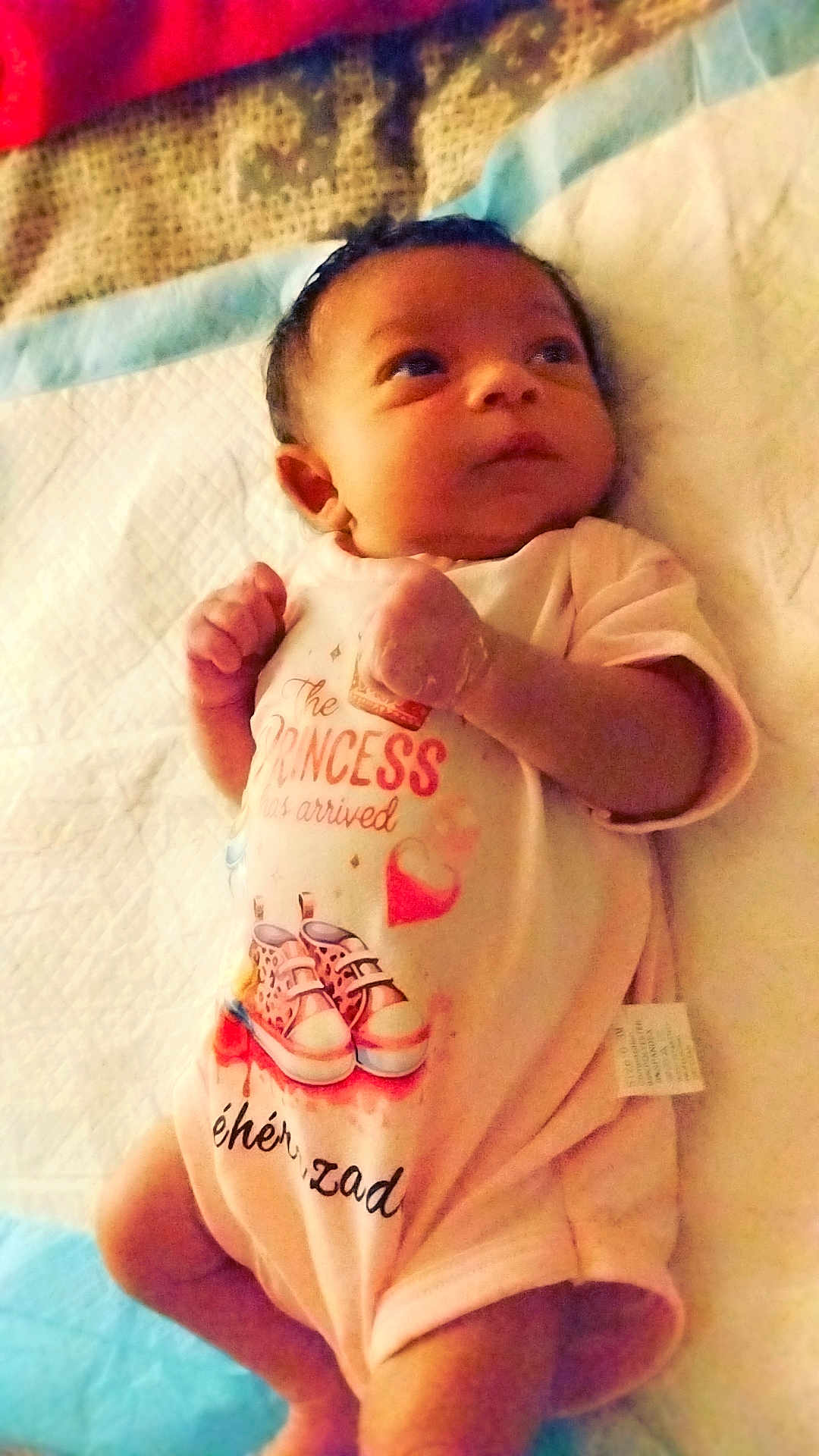 Shéhérazade a rejoint le concours — aidez-le/la à gagner de superbes lots ! baby, infant, onesie, newborn, lying_down, blanket, bed, face, eyes, hands, fingers, cute, portrait, indoor, textile, pattern, pink, decorative, sheet, mattress