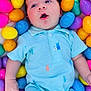 Carter joined the competition — help win amazing prizes! baby, infant, easter_eggs, plastic_eggs, onesie, blue_onesie, colorful, portrait, closeup, open_mouth, blanket, cute, lying_down, hand, arm, soft_texture, playful, holiday, decor, smile
