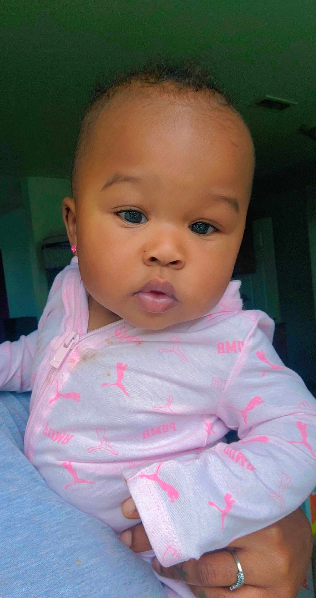 Knowing is registered to the contest to win money with this photo: baby, child, face, pink_clothing, puma_logo, earrings, hand, ring, indoor, portrait, cute, infant, person, young_child, skin, eyes, long_sleeve, holding, cozy, close_up