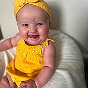 Oaklee Mae joined the competition — help win amazing prizes! baby, child, smile, yellow_clothing, headband, happy, infant, person, cute, sitting, blanket, soft, indoors, portrait, skin, face, hand, bright, young, comfortable