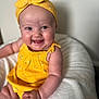 baby, child, smile, yellow_clothing, headband, happy, infant, person, cute, sitting, blanket, soft, indoors, portrait, skin, face, hand, bright, young, comfortable