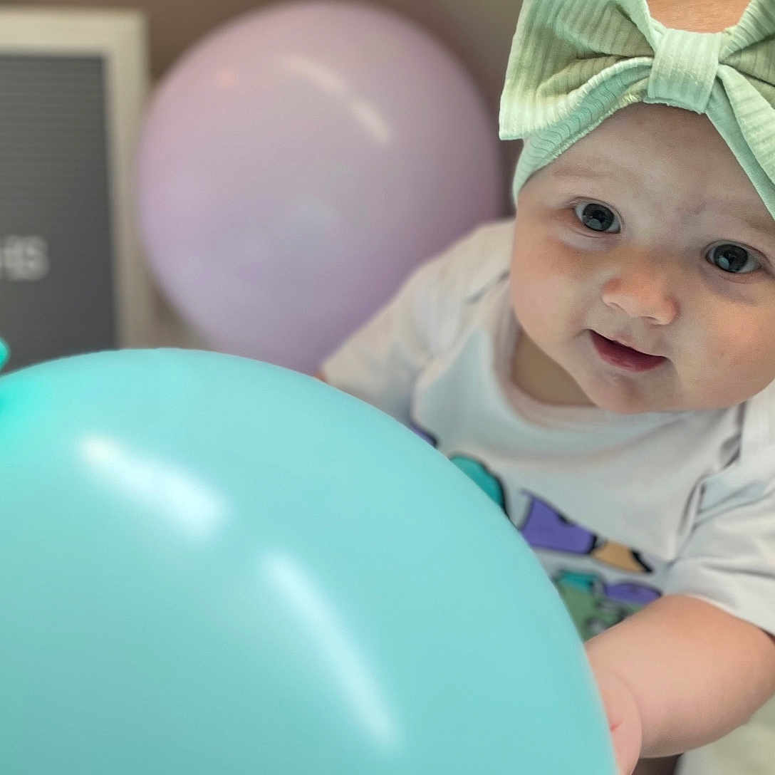 Oaklee Mae joined the competition — help win amazing prizes! baby, balloon, blue_balloon, celebration, child, chubby_cheeks, cute, headband, indoor, infant, mint_green, pastel_colors, playful, portrait, sign, six_months, smiling, soft_light, white_clothing, young_child