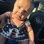 baby, child, infant, pout, car_interior, steering_wheel, hand, clothing, sunlight, face, person, portrait, seat, blue_clothing, star_pattern, lace, skin, expression, closeup, vehicle