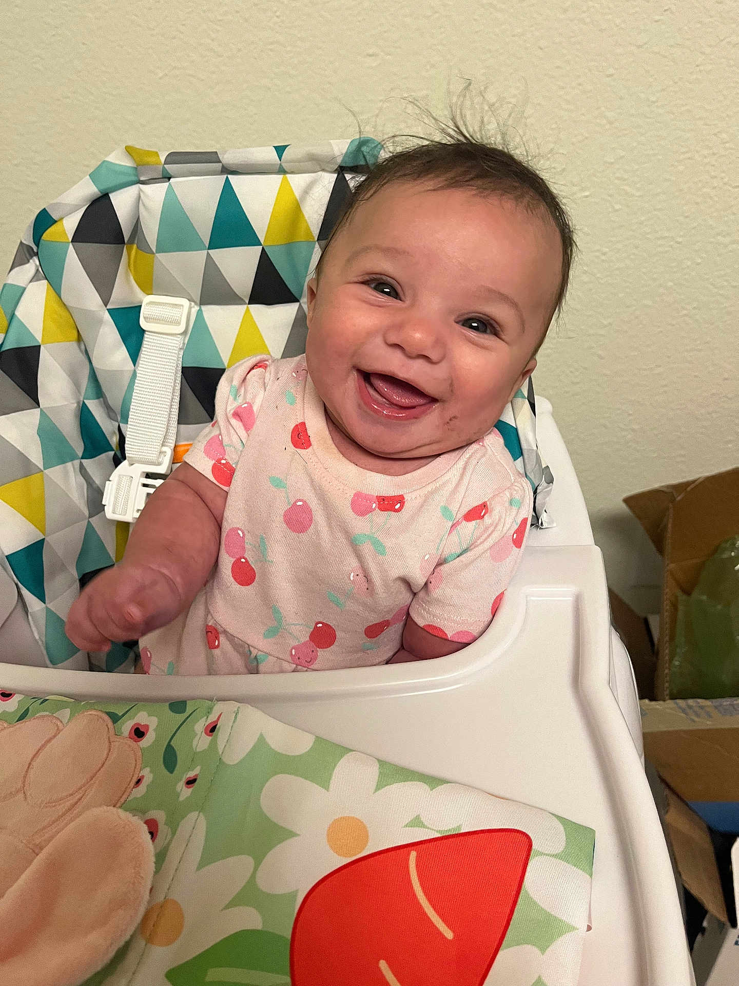 Tianna joined the competition — help win amazing prizes! baby, smiling, high_chair, child, infant, happy, face, clothing, patterned_fabric, home, indoor, cheerful, cute, toddler, seat_belt, colorful, portrait, person, young_child, fun
