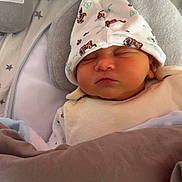 Axel participe au concours pour gagner de l'argent avec cette photo : baby, newborn, sleeping, hat, cute, cozy, blanket, cushion, soft, infant, face, indoors, resting, peaceful, child, apparel, headwear, person, portrait, comfort