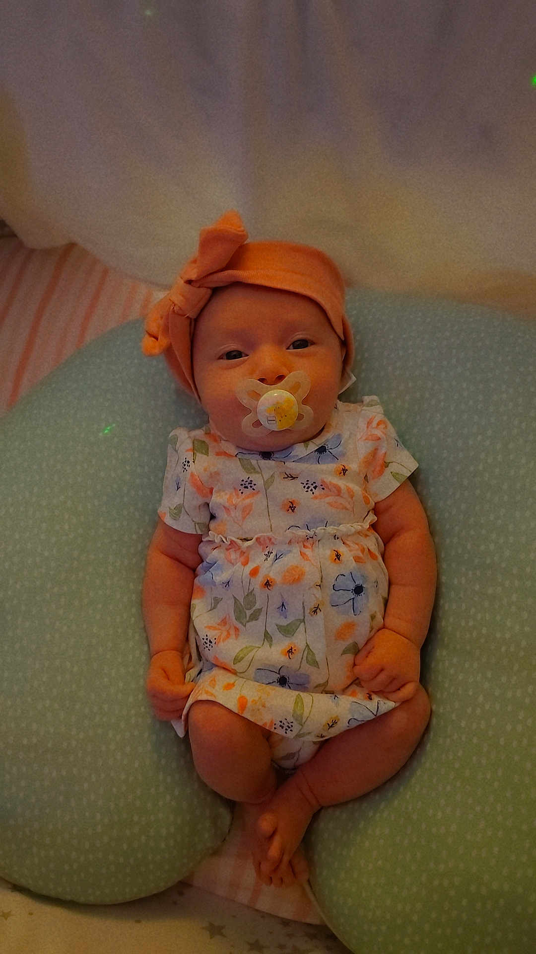 Ka'Lani Grace joined the competition — help win amazing prizes! baby, infant, pacifier, headband, floral_dress, cushion, soft_furniture, indoor, sleeping_area, cute, child, newborn, resting, comfort, small_hands, small_feet, portrait, peaceful, lying_down, closeup