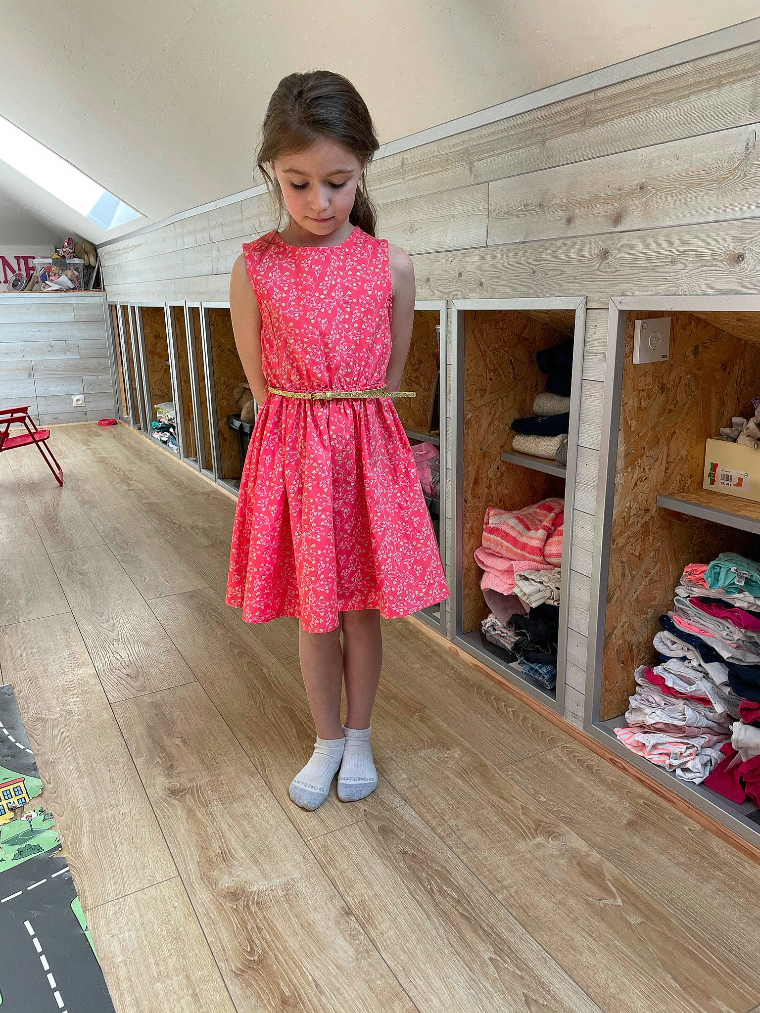 Roxane participe au concours pour gagner de l'argent avec cette photo : blond, day_dress, dress, fashion_design, floor, flooring, hardwood, human_leg, leg, magenta, one_piece_garment, pattern, person, shelf, sleeve, thigh, toy, trunk, waist, wood