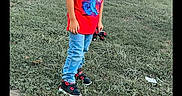 Xadiel Estévez is registered to the contest to win money with this photo: boy, casual_clothing, child, curious, daylight, grass, greenery, jeans, nature, outdoor, park, playing, portrait, recycling_bins, red_tshirt, sneakers, standing, toy_car, trees, young