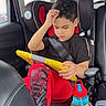 Xadiel Estévez joined the competition — help win amazing prizes! child, boy, car_seat, tablet, red_pants, black_shirt, seatbelt, water_bottle, car_interior, window, daylight, focused, sitting, technology, child_safety, vehicle, casual_clothing, curly_hair, young, indoors