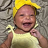 baby, smiling, yellow_headband, yellow_outfit, infant, happy, lying_down, blanket, cute, child, portrait, skin, face, hand, headwear, fabric, closeup, indoors, newborn, cheerful