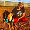 Tigrou participe au concours pour gagner de l'argent avec cette photo : affection, black_tshirt, casual_clothing, compassion, disability, dog, earth, fence, glasses, headscarf, kneeling, outdoor, pet, red_pants, shadow, sky, sunlight, text_on_clothing, wheelchair, woman
