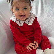 Esmée a rejoint le concours — aidez-le/la à gagner de superbes lots ! baby, child, smiling, red_clothing, white_collar, pigtails, sitting, happy, cute, portrait, indoor, cozy, sock, knitwear, infant, face, hands, blanket, young_child, expression