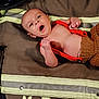 baby, infant, firefighter_jacket, crocheted_clothing, yawning, clenched_fists, helmet, fabric, text, brown, red, person, laying_down, cute, newborn, closeup, indoor, apparel, head, expression