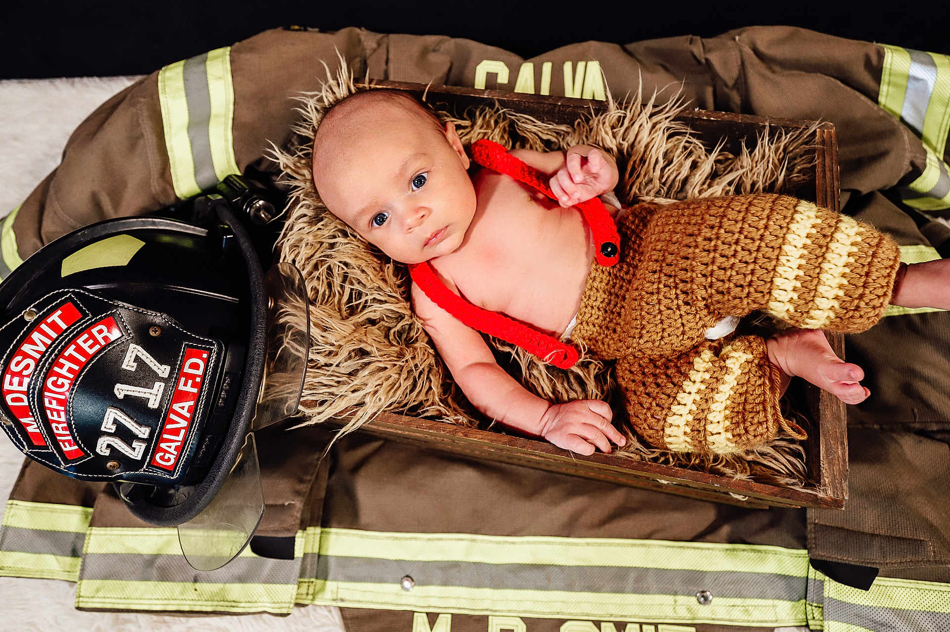 Bryson joined the competition — help win amazing prizes! baby, baby_clothes, blue_eyes, closeup, crocheted_pants, cute, firefighter_gear, firefighter_helmet, firefighter_jacket, fur_lining, indoors, infant, light_skin, newborn, person, portrait, red_suspender, resting, soft_texture, wooden_box