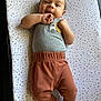 baby, barefoot, blanket, child, clothing, cute, face, foot, grey_shirt, hand, happy, head, indoors, infant, lying_down, pants, portrait, skin, smiling, star_pattern