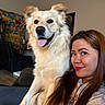 dog, woman, indoor, smile, tongue_out, long_hair, casual_clothing, sofa, poster, wall_art, brown_hair, light_fur, pet, happy, portrait, face, seated, cozy, living_room, friendship