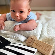 Benjamin is registered to the contest to win money with this photo: baby, infant, child, blanket, wooden_blocks, milestone, 3_months, soft_texture, lying_down, cute, curious, indoors, close_up, black_and_white, striped, book, skin, face, person, young