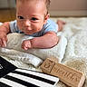 baby, infant, child, blanket, wooden_blocks, milestone, 3_months, soft_texture, lying_down, cute, curious, indoors, close_up, black_and_white, striped, book, skin, face, person, young