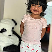 Zunairah is registered to the contest to win money with this photo: child, girl, smiling, portrait, indoors, pajamas, pink_shirt, cherry_pattern, black_hair, curly_hair, standing, happy, plush_toy, panda, bedroom, home, window, soft_lighting, casual_clothing, person
